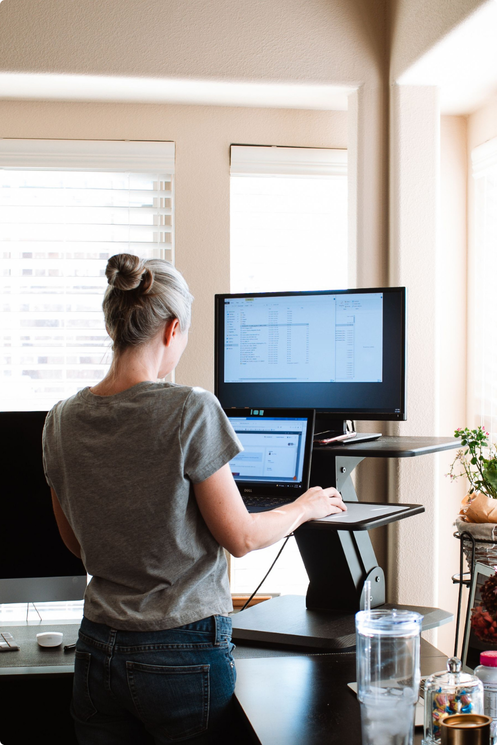 Employee working from home at a standing desk with dual monitors, representing flexible work compliance software for Australian employers