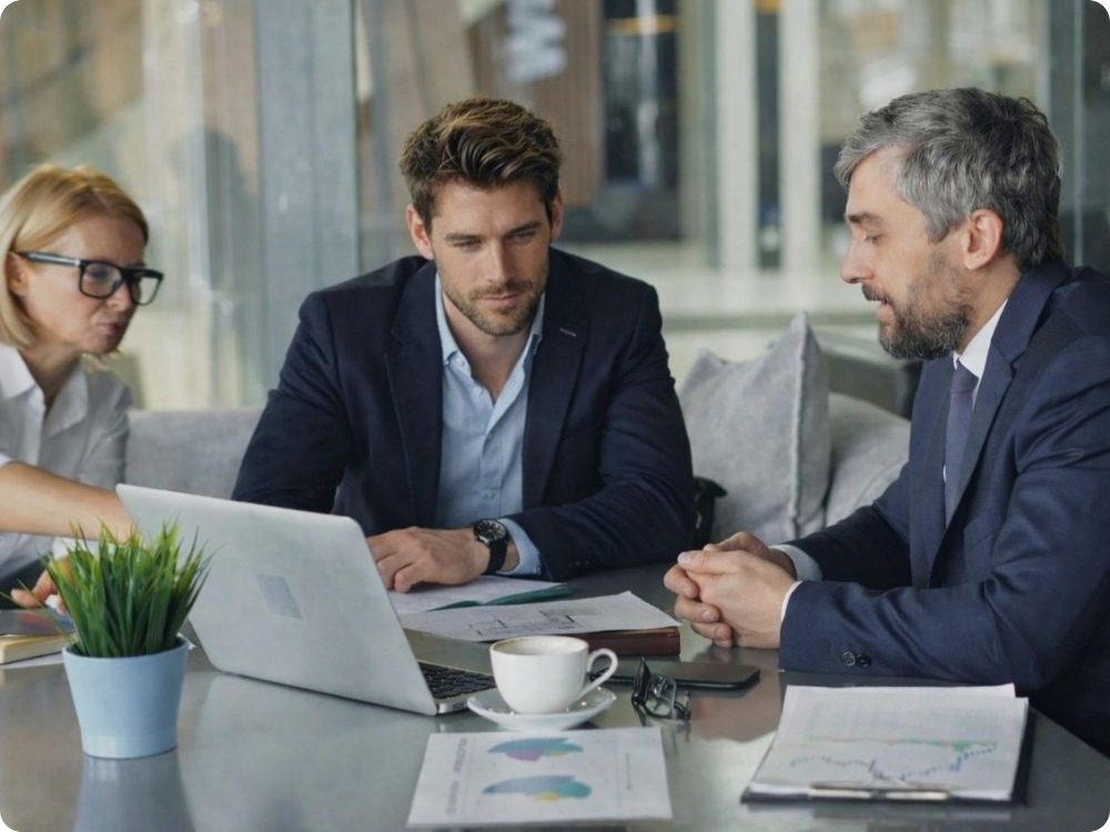 Consultant presenting to two clients over a laptop in a meeting, representing an HR compliance platform Australia partners use to build recurring revenue